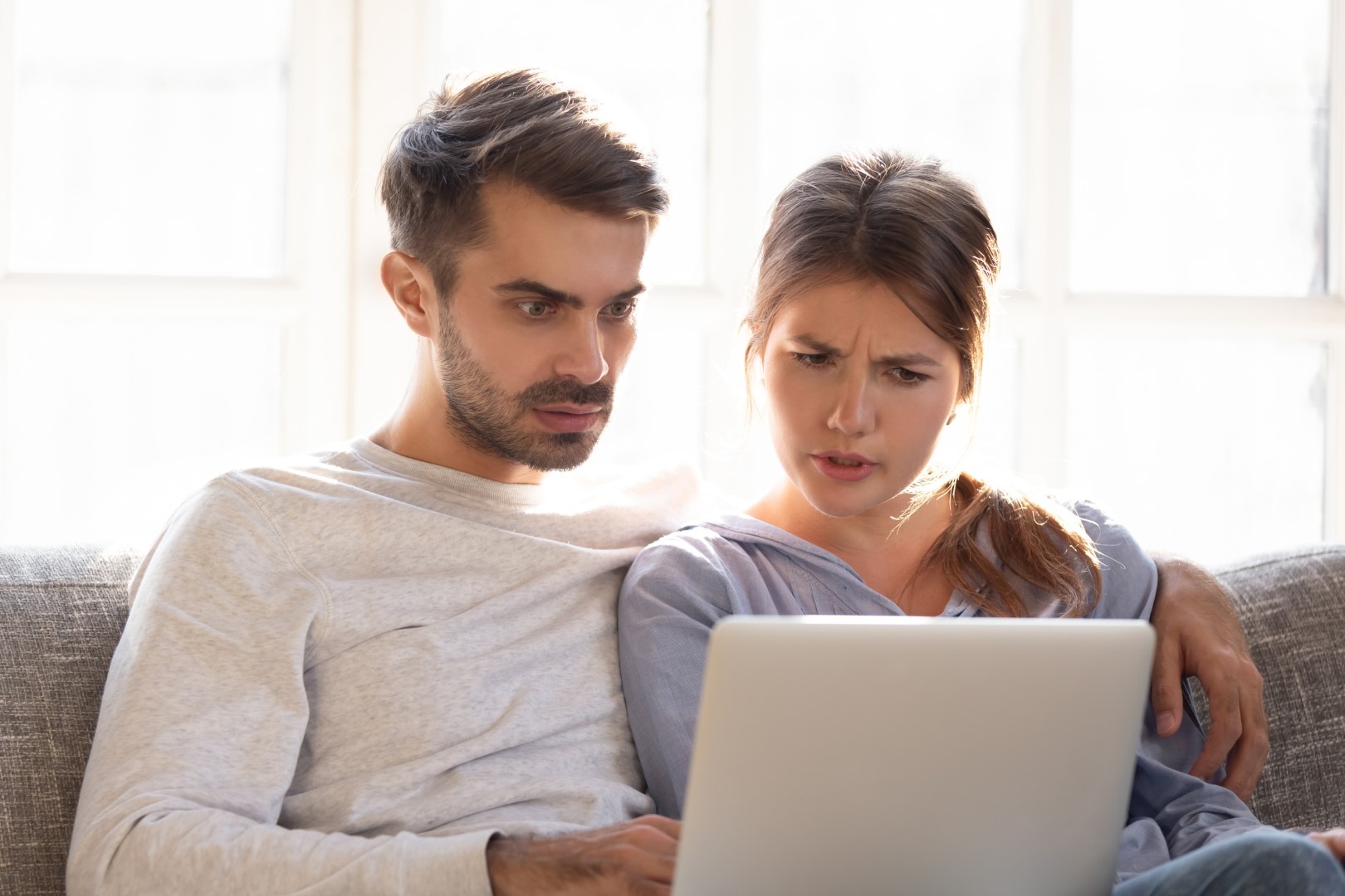 Confused baffled wife and shocked frustrated husband reading an email from their homebuyer.